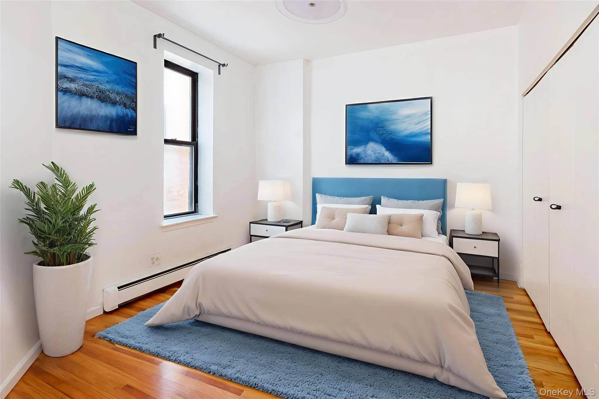 Bedroom featuring a baseboard heating unit and light wood-style floors Bedroom featuring a baseboard heating unit and light wood-style floors