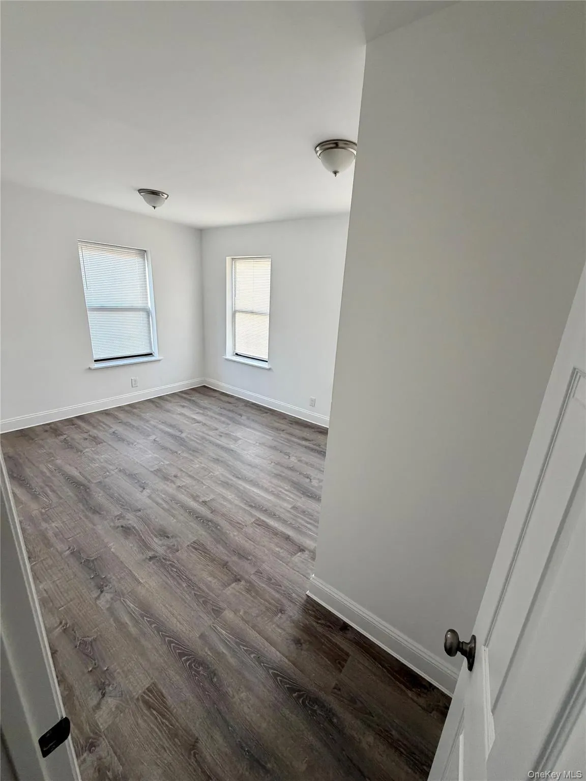 Unfurnished room with dark wood-style flooring and baseboards Unfurnished room with dark wood-style flooring and baseboards