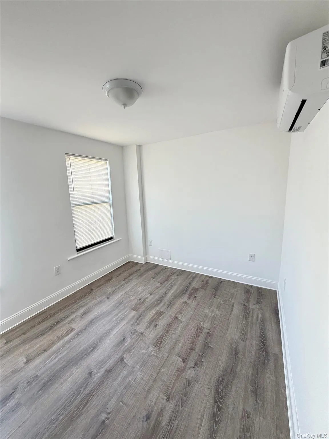 Empty room featuring wood finished floors and a wall mounted AC Empty room featuring wood finished floors and a wall mounted AC