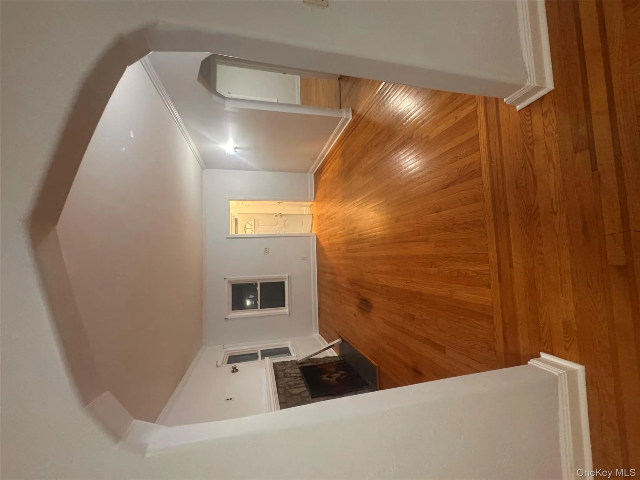 Unfurnished living room with arched walkways, crown molding, wood-type flooring, and a fireplace with flush hearth Unfurnished living room with arched walkways, crown molding, wood-type flooring, and a fireplace with flush hearth