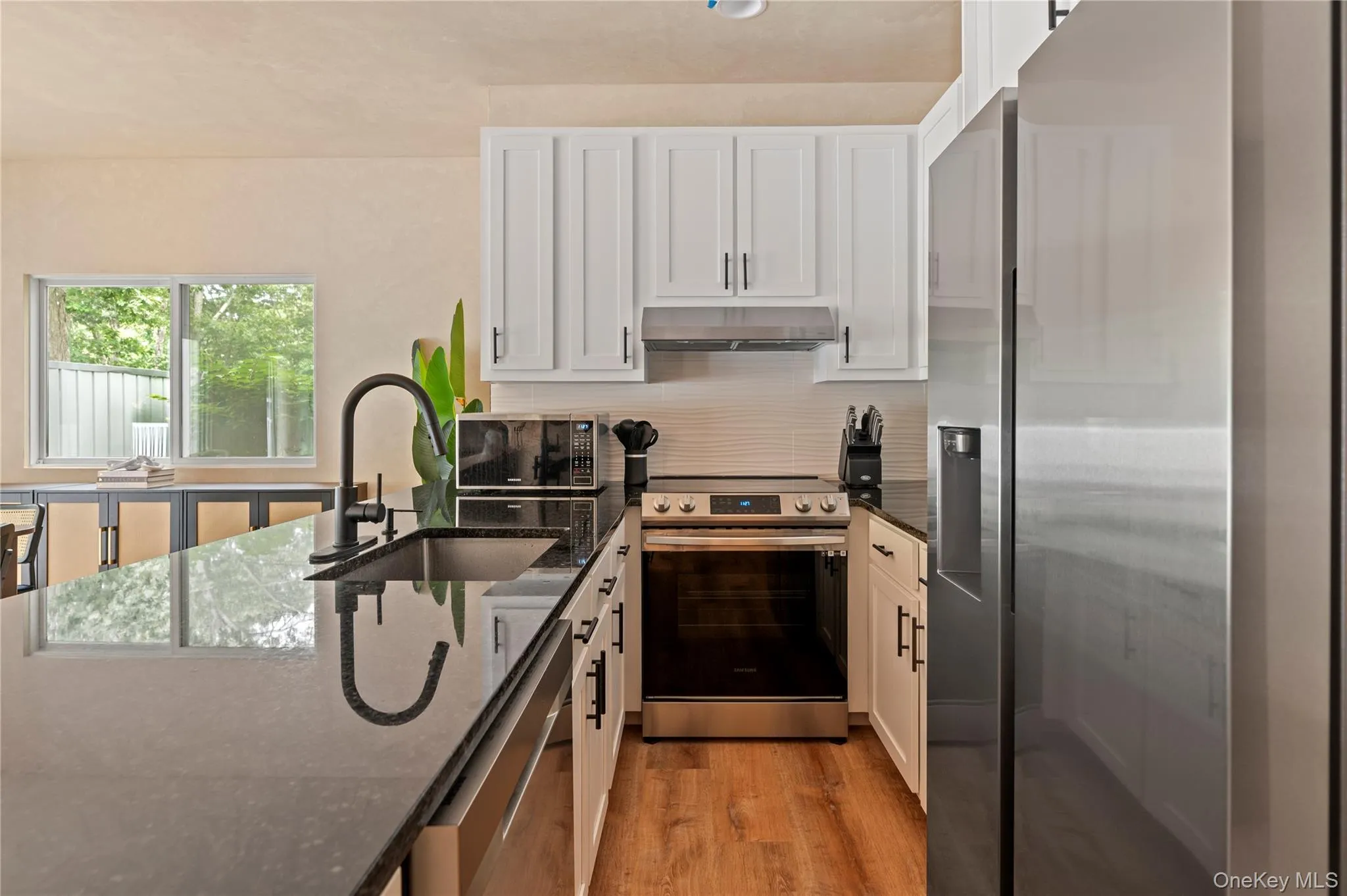 Kitchen featuring dark stone countertops, a sink, white cabinetry, stainless steel appliances, and extractor fan Kitchen featuring dark stone countertops, a sink, white cabinetry, stainless steel appliances, and extractor fan