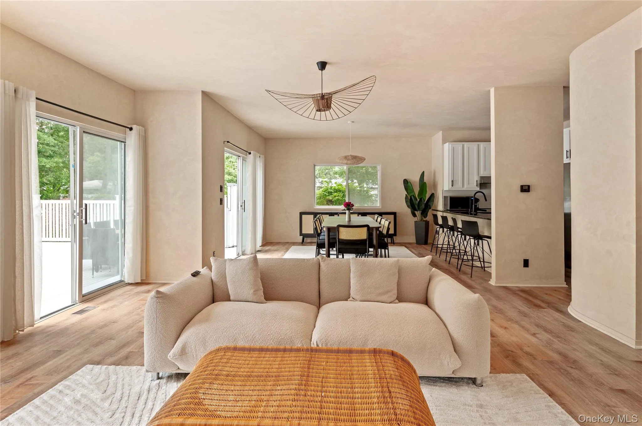 Living room with visible vents, light wood finished floors, baseboards, and plenty of natural light Living room with visible vents, light wood finished floors, baseboards, and plenty of natural light