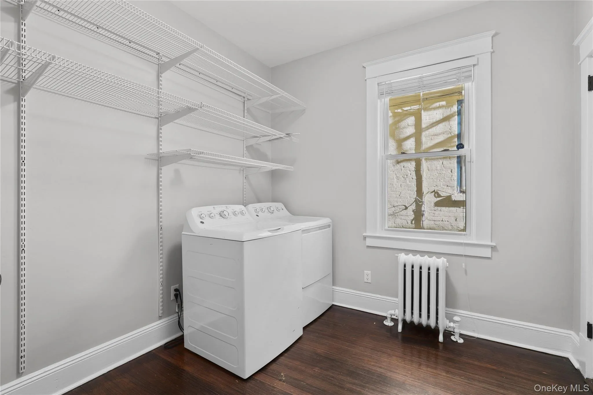 Laundry area with radiator, dark wood-style floors, and washer and dryer Laundry area with radiator, dark wood-style floors, and washer and dryer
