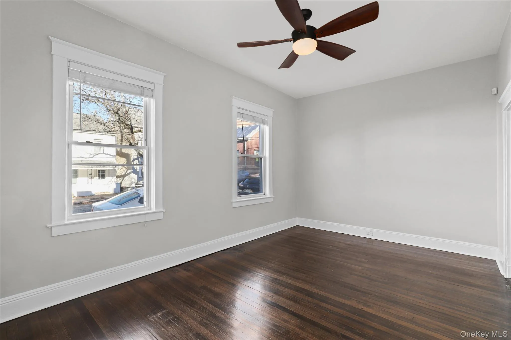 Unfurnished room featuring dark wood-style floors and a ceiling fan Unfurnished room featuring dark wood-style floors and a ceiling fan