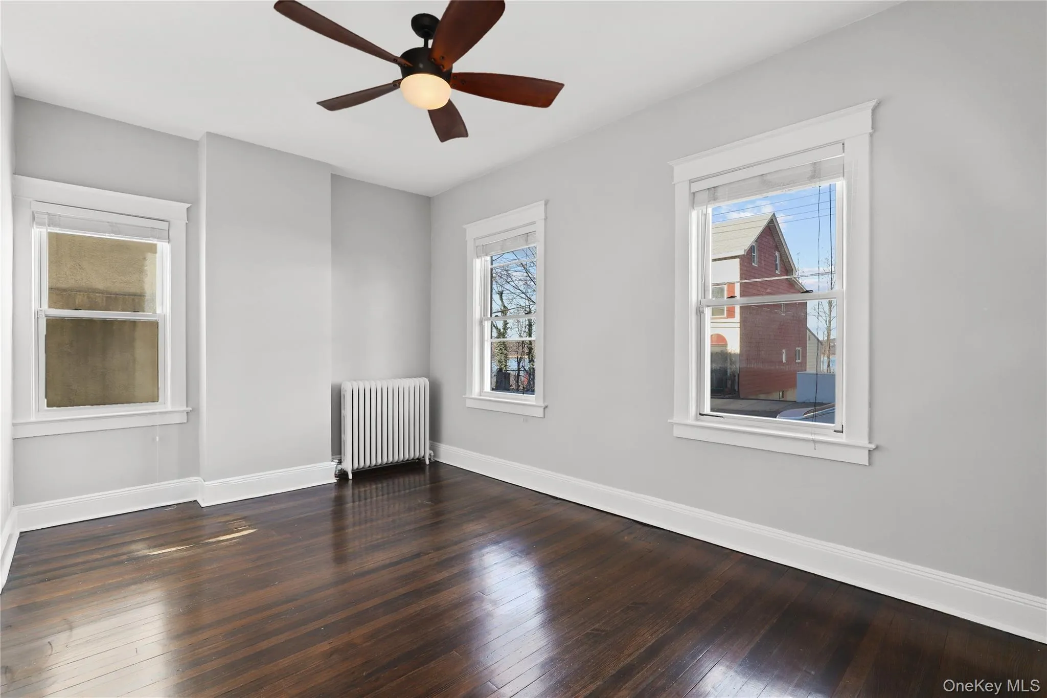 Spare room featuring radiator, dark wood finished floors, and a ceiling fan Spare room featuring radiator, dark wood finished floors, and a ceiling fan