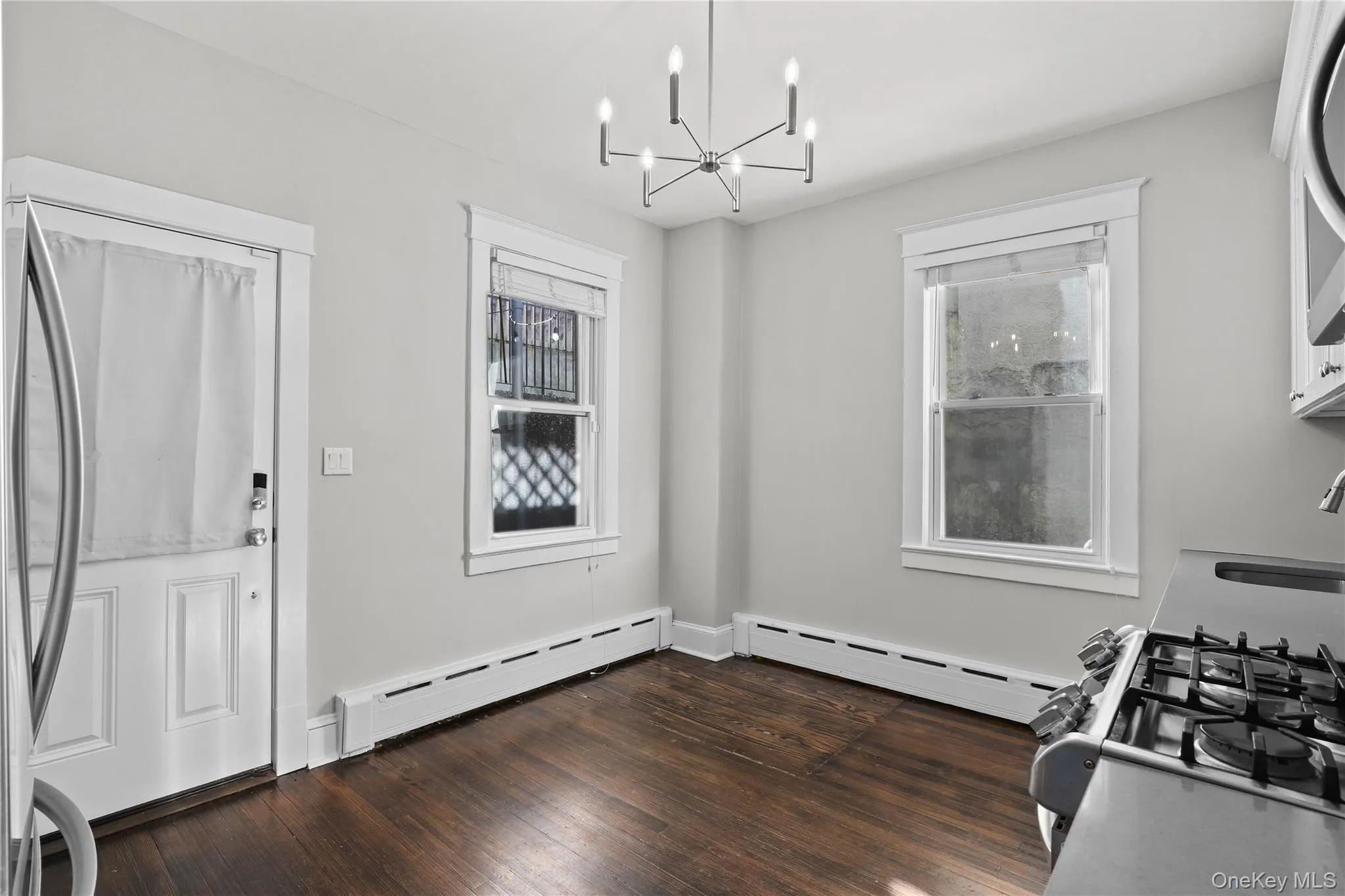 Unfurnished dining area with baseboard heating, a chandelier, and dark wood-style floors Unfurnished dining area with baseboard heating, a chandelier, and dark wood-style floors