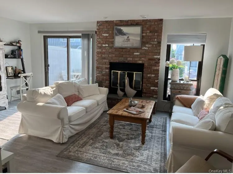 Living room featuring a fireplace, plenty of natural light, and wood finished floors Living room featuring a fireplace, plenty of natural light, and wood finished floors