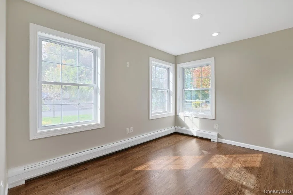 Unfurnished room featuring baseboard heating, wood finished floors, and recessed lighting Unfurnished room featuring baseboard heating, wood finished floors, and recessed lighting