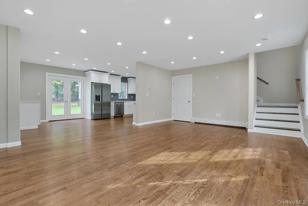 Unfurnished living room featuring stairs, light wood-style flooring, and recessed lighting Unfurnished living room featuring stairs, light wood-style flooring, and recessed lighting