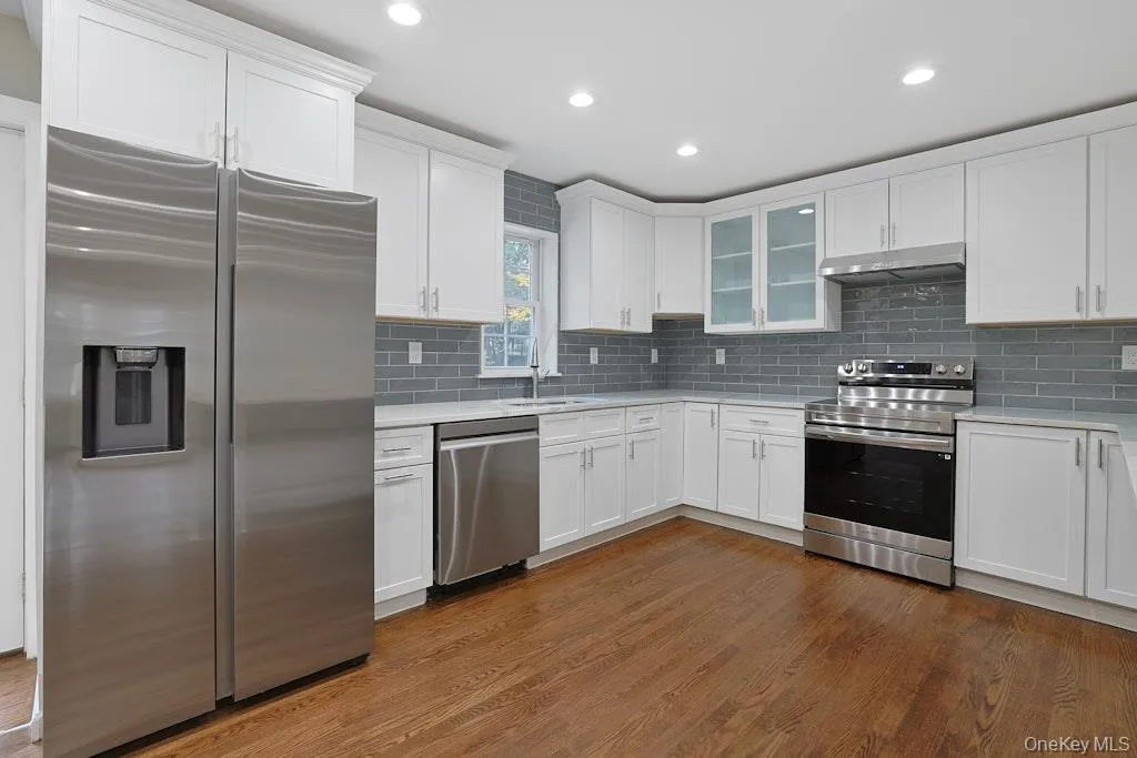 Kitchen featuring stainless steel appliances, white cabinets, dark wood-type flooring, backsplash, and recessed lighting Kitchen featuring stainless steel appliances, white cabinets, dark wood-type flooring, backsplash, and recessed lighting