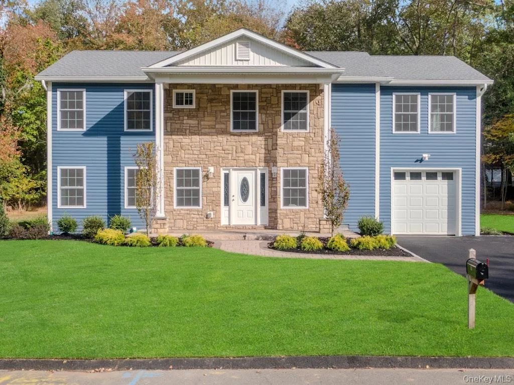 View of front of property featuring stone siding, a front yard, driveway, and a garage View of front of property featuring stone siding, a front yard, driveway, and a garage