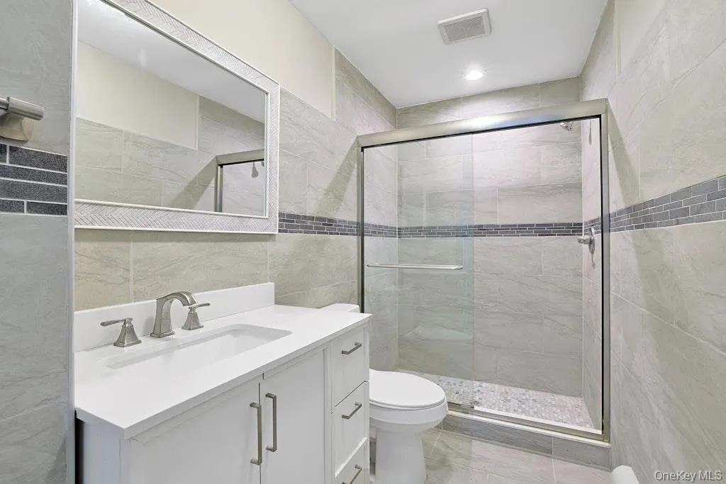Bathroom featuring tile walls, vanity, a shower stall, and recessed lighting Bathroom featuring tile walls, vanity, a shower stall, and recessed lighting