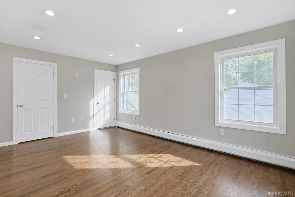 Unfurnished bedroom with baseboard heating, wood finished floors, recessed lighting, and a closet Unfurnished bedroom with baseboard heating, wood finished floors, recessed lighting, and a closet