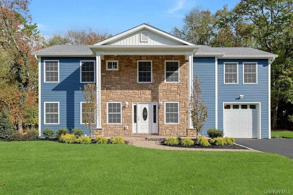 View of front of home with a front yard, stone siding, asphalt driveway, and an attached garage View of front of home with a front yard, stone siding, asphalt driveway, and an attached garage