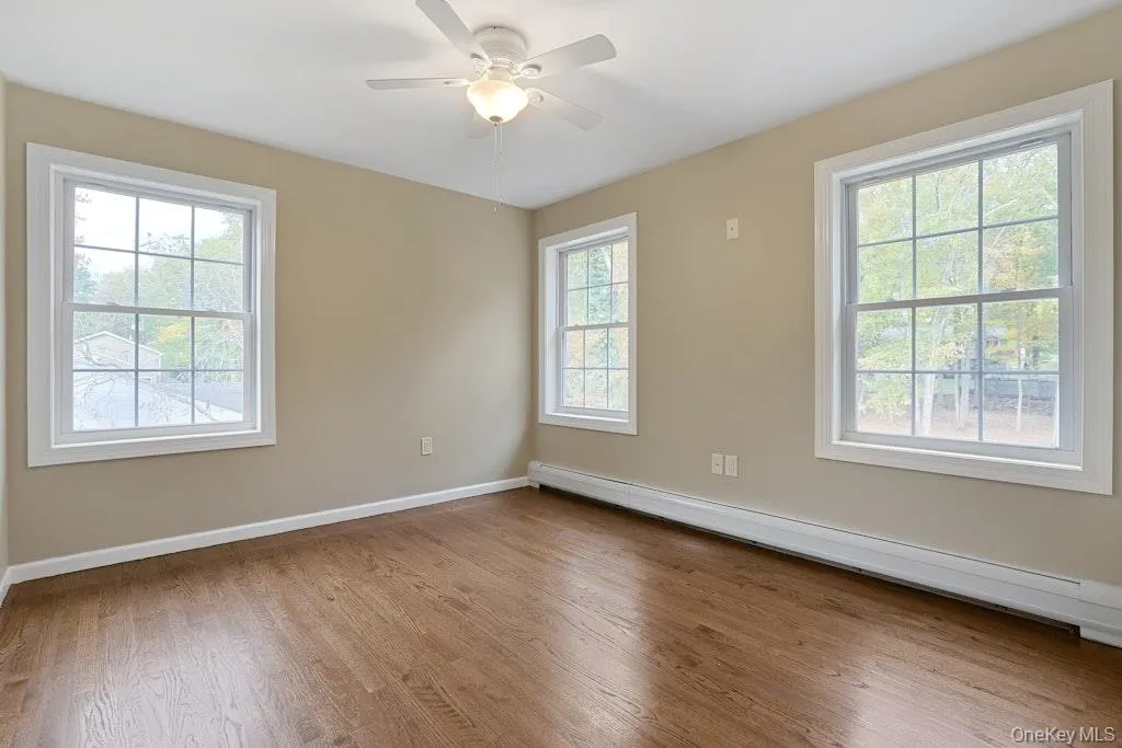 Unfurnished room featuring a baseboard heating unit, light wood-style floors, and a ceiling fan Unfurnished room featuring a baseboard heating unit, light wood-style floors, and a ceiling fan