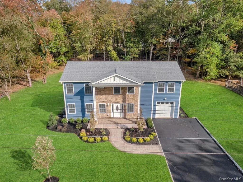 View of front facade with a front lawn, driveway, a garage, and stone siding View of front facade with a front lawn, driveway, a garage, and stone siding