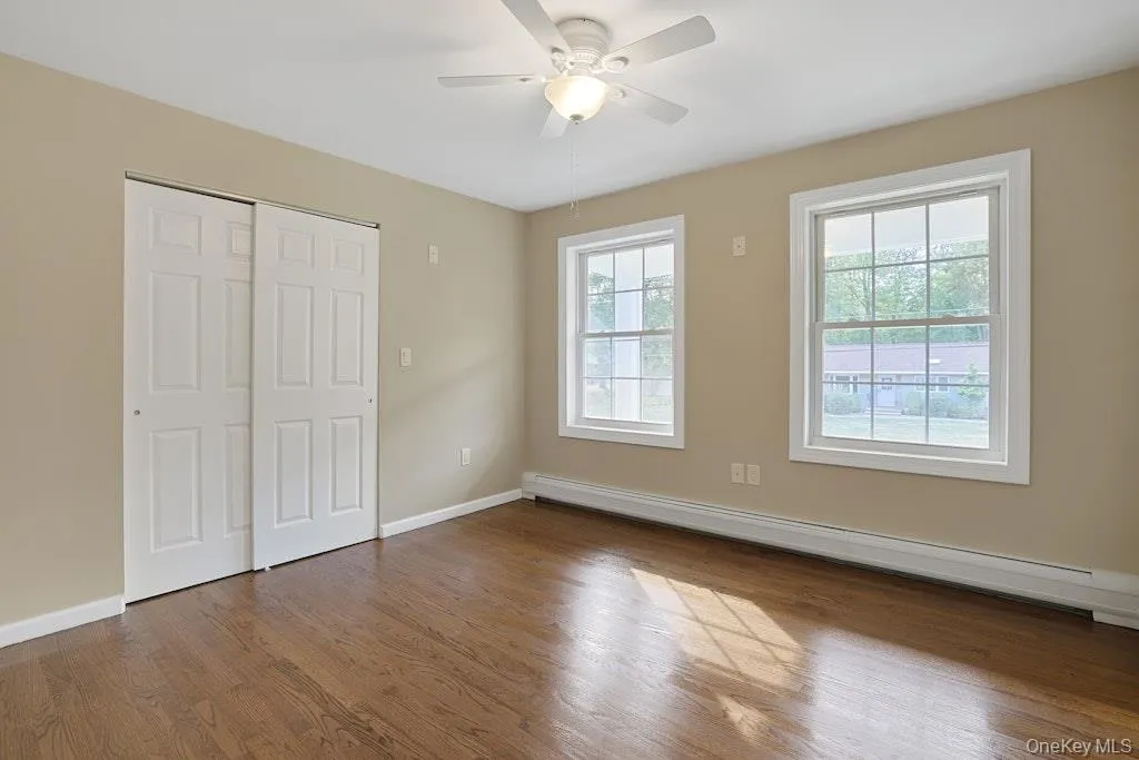Unfurnished bedroom featuring baseboard heating, wood finished floors, a closet, and ceiling fan Unfurnished bedroom featuring baseboard heating, wood finished floors, a closet, and ceiling fan