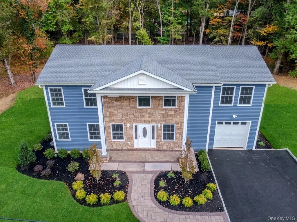 View of front of home with a front yard, driveway, stone siding, roof with shingles, and an attached garage View of front of home with a front yard, driveway, stone siding, roof with shingles, and an attached garage