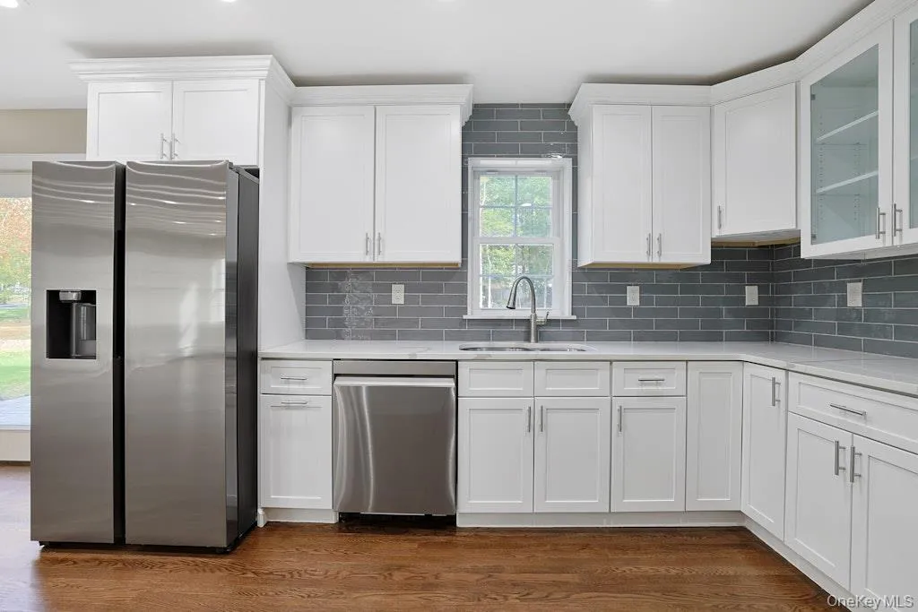 Kitchen with appliances with stainless steel finishes, white cabinetry, tasteful backsplash, light stone countertops, and recessed lighting Kitchen with appliances with stainless steel finishes, white cabinetry, tasteful backsplash, light stone countertops, and recessed lighting
