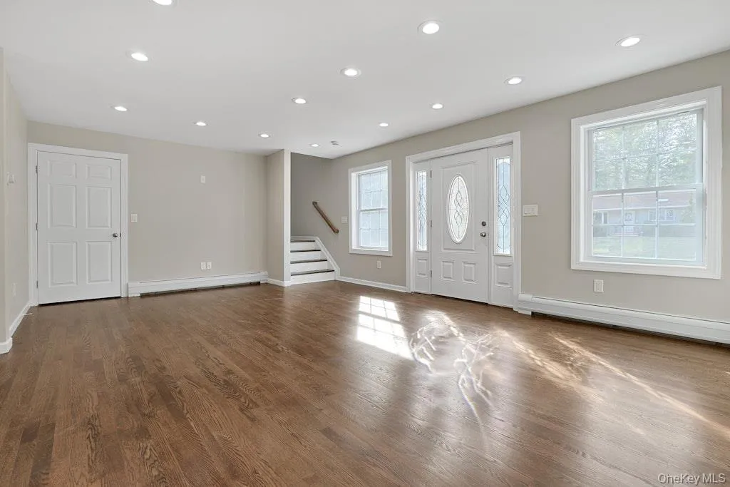 Foyer with stairs, dark wood-type flooring, recessed lighting, and a baseboard radiator Foyer with stairs, dark wood-type flooring, recessed lighting, and a baseboard radiator