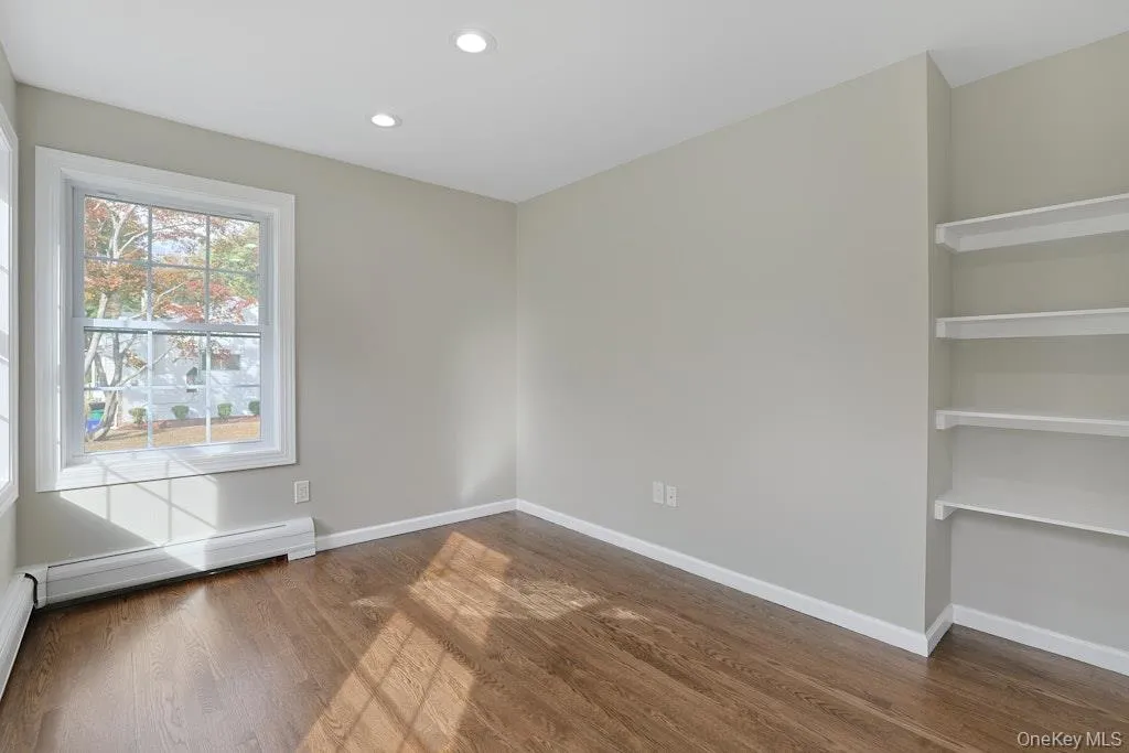 Spare room featuring dark wood-type flooring, recessed lighting, and a baseboard radiator Spare room featuring dark wood-type flooring, recessed lighting, and a baseboard radiator