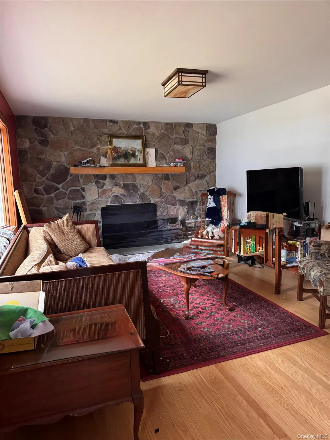 Living area with a stone fireplace and wood finished floors Living area with a stone fireplace and wood finished floors