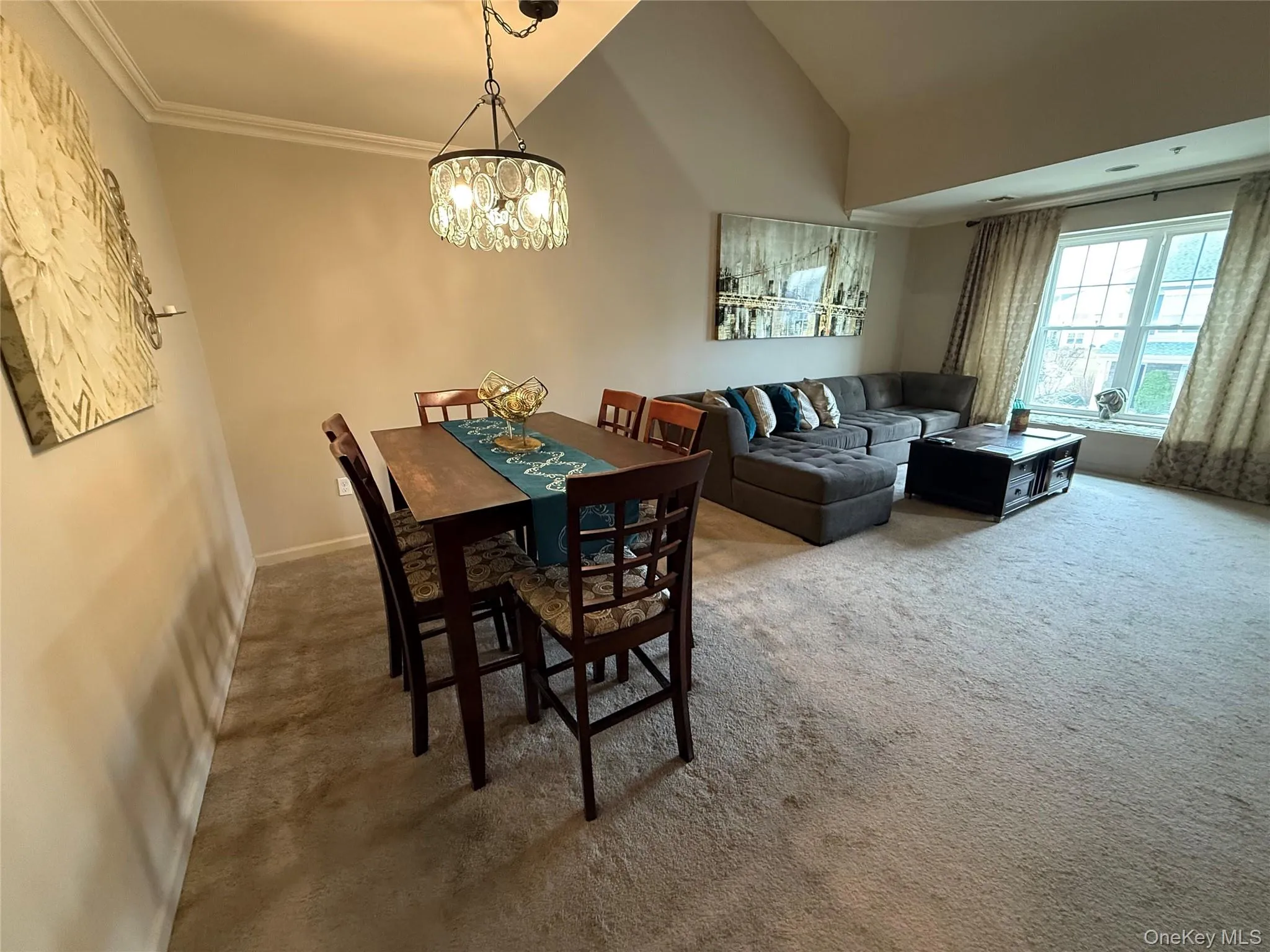 Carpeted dining area featuring vaulted ceiling, crown molding, and a chandelier. Carpeted dining area featuring vaulted ceiling, crown molding, and a chandelier.