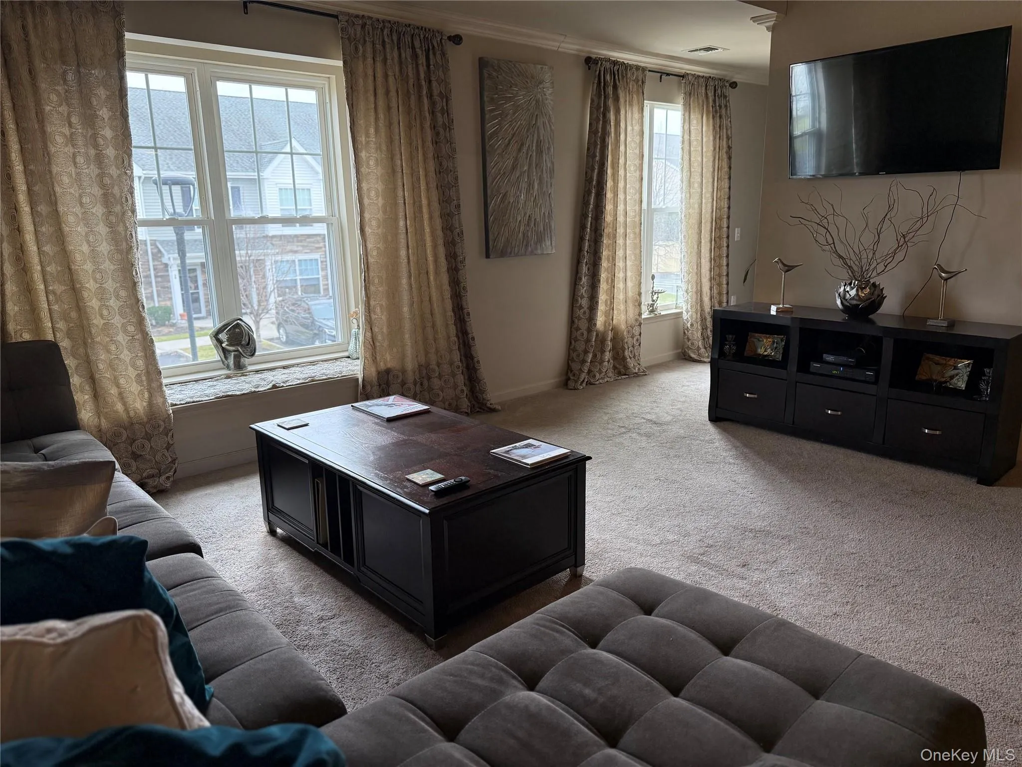 Living room with light colored carpet, plenty of natural light, and crown molding. Living room with light colored carpet, plenty of natural light, and crown molding.