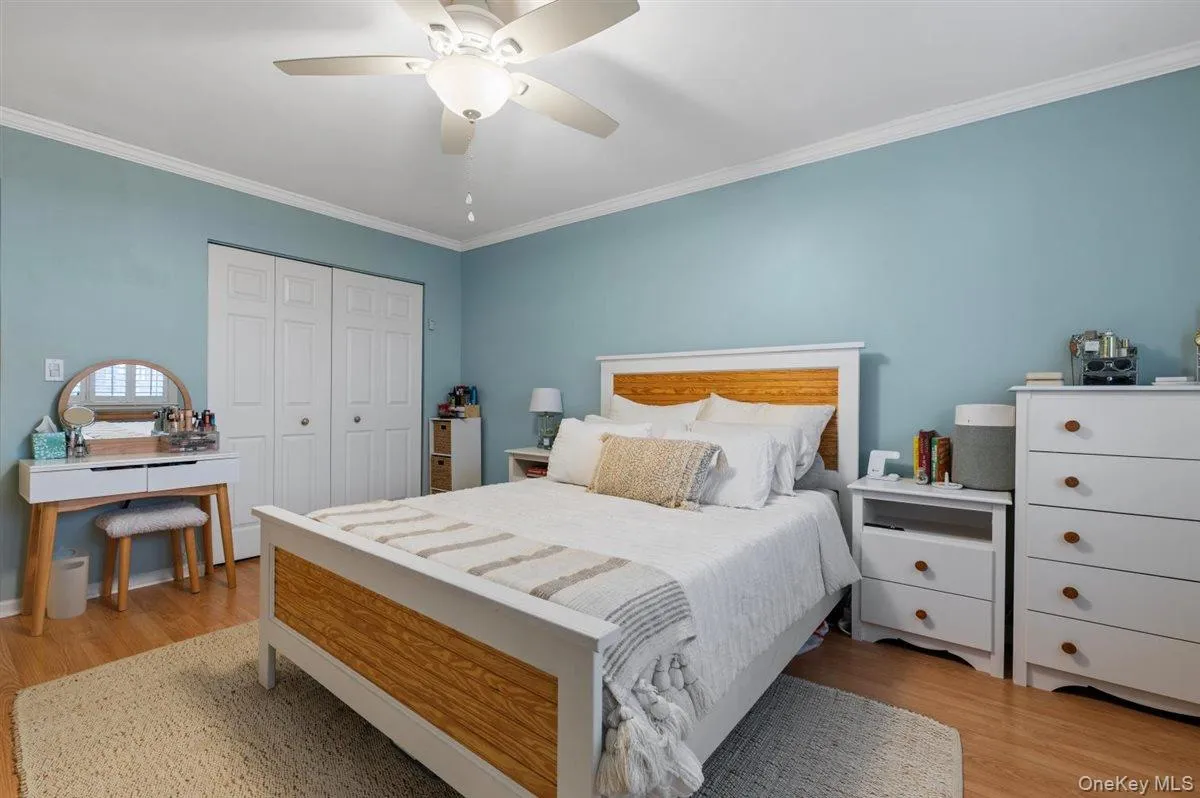 Bedroom with crown molding, a ceiling fan, a closet, and light wood finished floors Bedroom with crown molding, a ceiling fan, a closet, and light wood finished floors