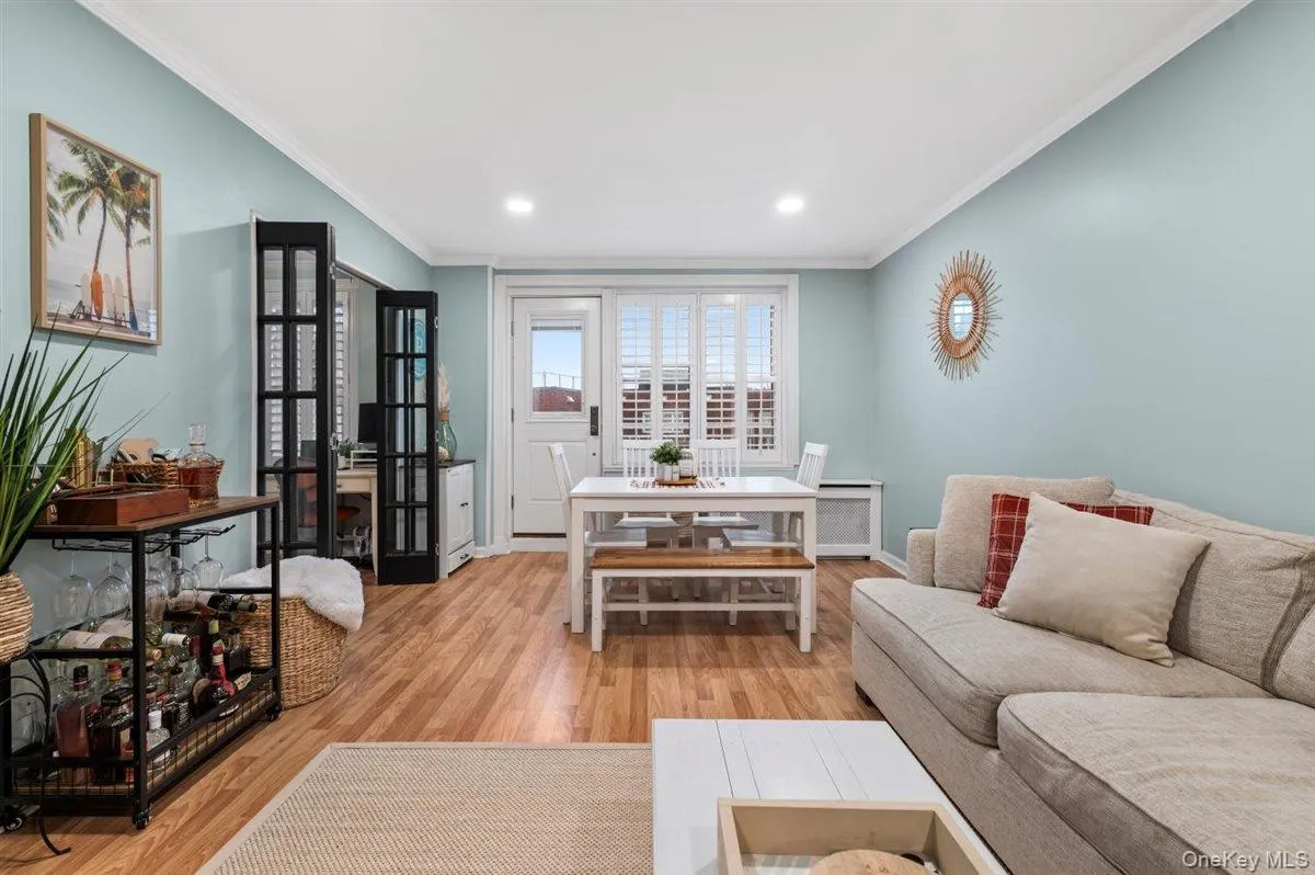 Living area featuring light wood-style flooring, recessed lighting, ornamental molding, and radiator Living area featuring light wood-style flooring, recessed lighting, ornamental molding, and radiator
