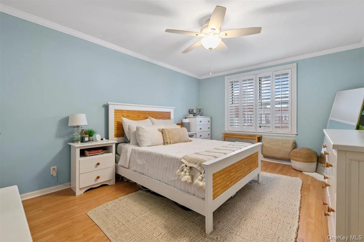 Bedroom with ornamental molding, a ceiling fan, and light wood-style flooring Bedroom with ornamental molding, a ceiling fan, and light wood-style flooring
