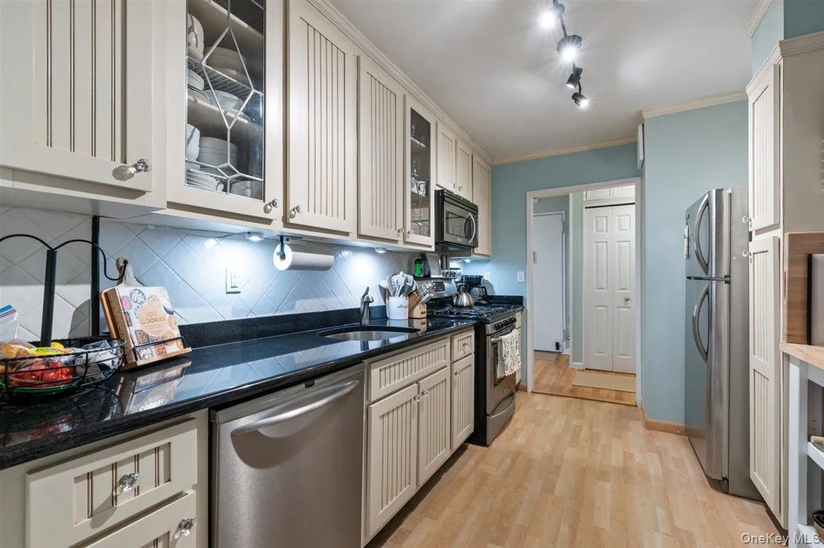 Kitchen featuring appliances with stainless steel finishes, glass insert cabinets, dark stone counters, decorative backsplash, and crown molding Kitchen featuring appliances with stainless steel finishes, glass insert cabinets, dark stone counters, decorative backsplash, and crown molding
