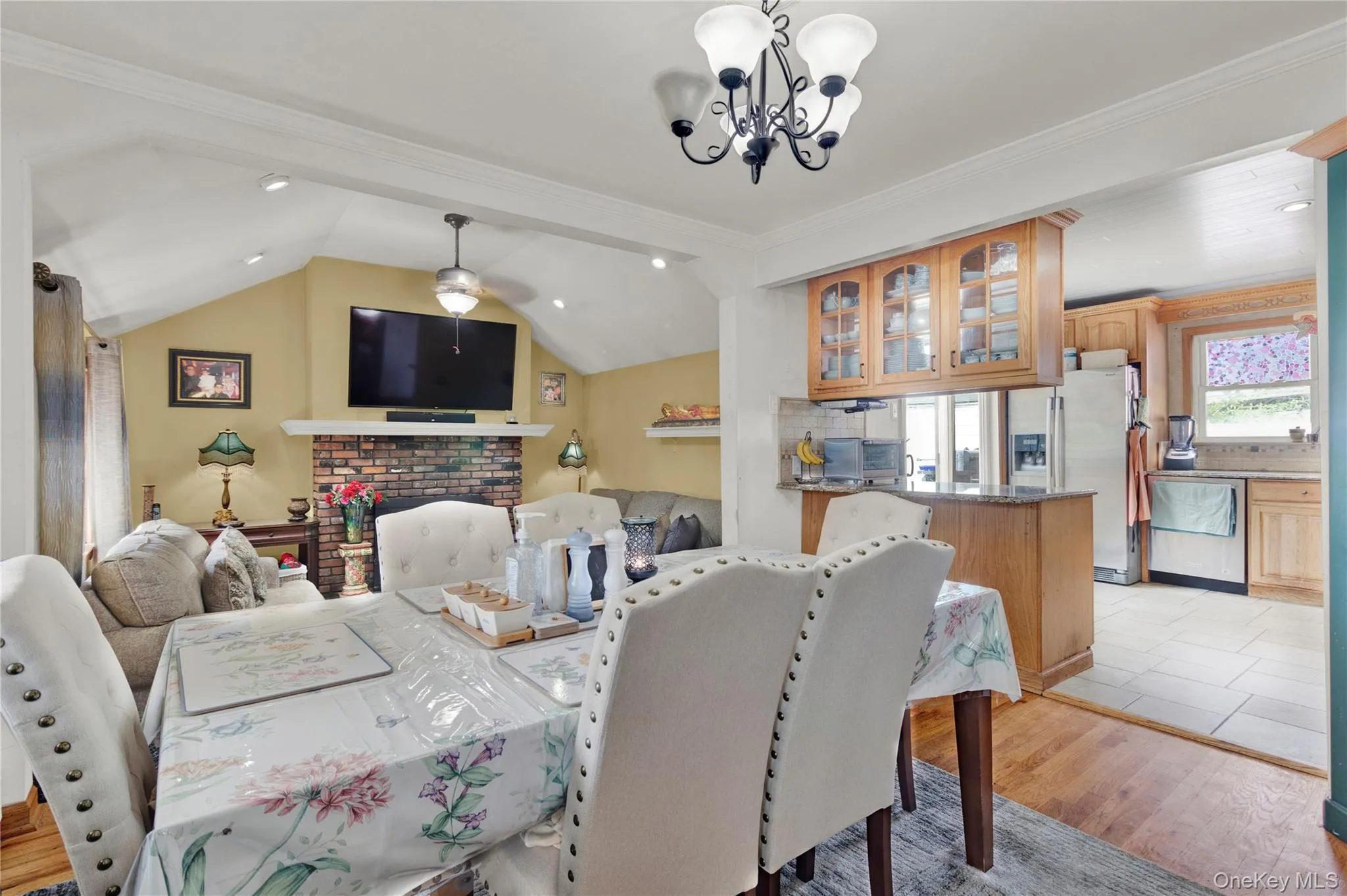 Dining area with a chandelier, light wood finished floors, lofted ceiling, ornamental molding, and recessed lighting Dining area with a chandelier, light wood finished floors, lofted ceiling, ornamental molding, and recessed lighting