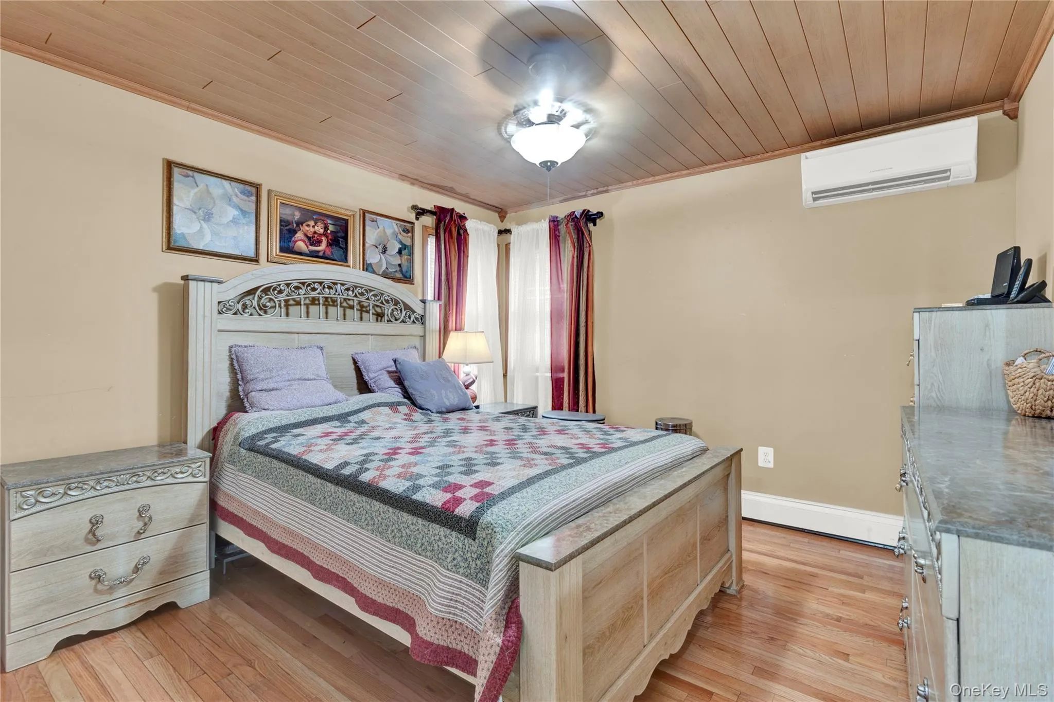 Bedroom featuring wooden ceiling, light wood finished floors, a wall unit AC, and ornamental molding Bedroom featuring wooden ceiling, light wood finished floors, a wall unit AC, and ornamental molding