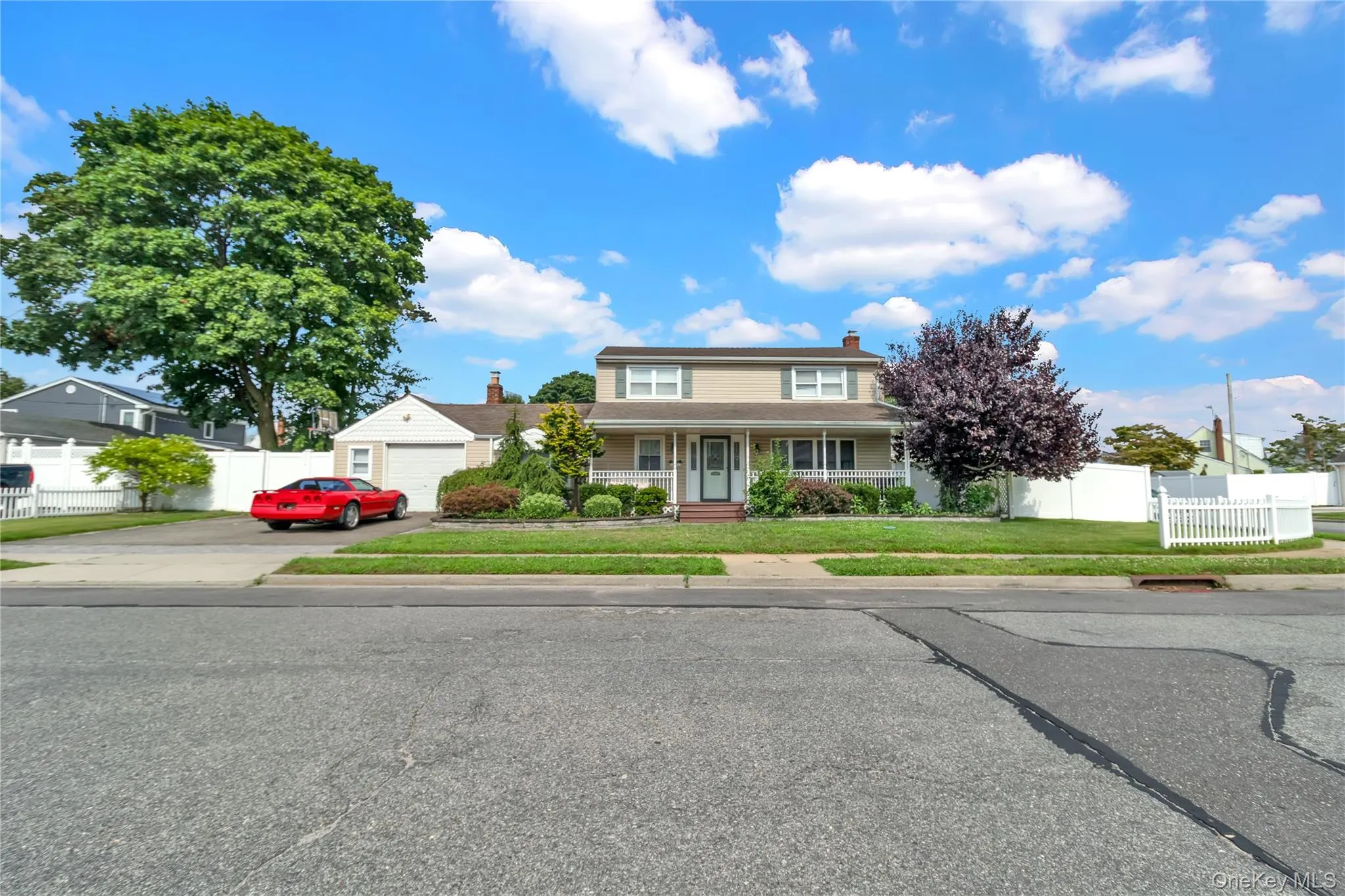 Traditional-style home featuring a porch, concrete driveway, and a chimney Traditional-style home featuring a porch, concrete driveway, and a chimney