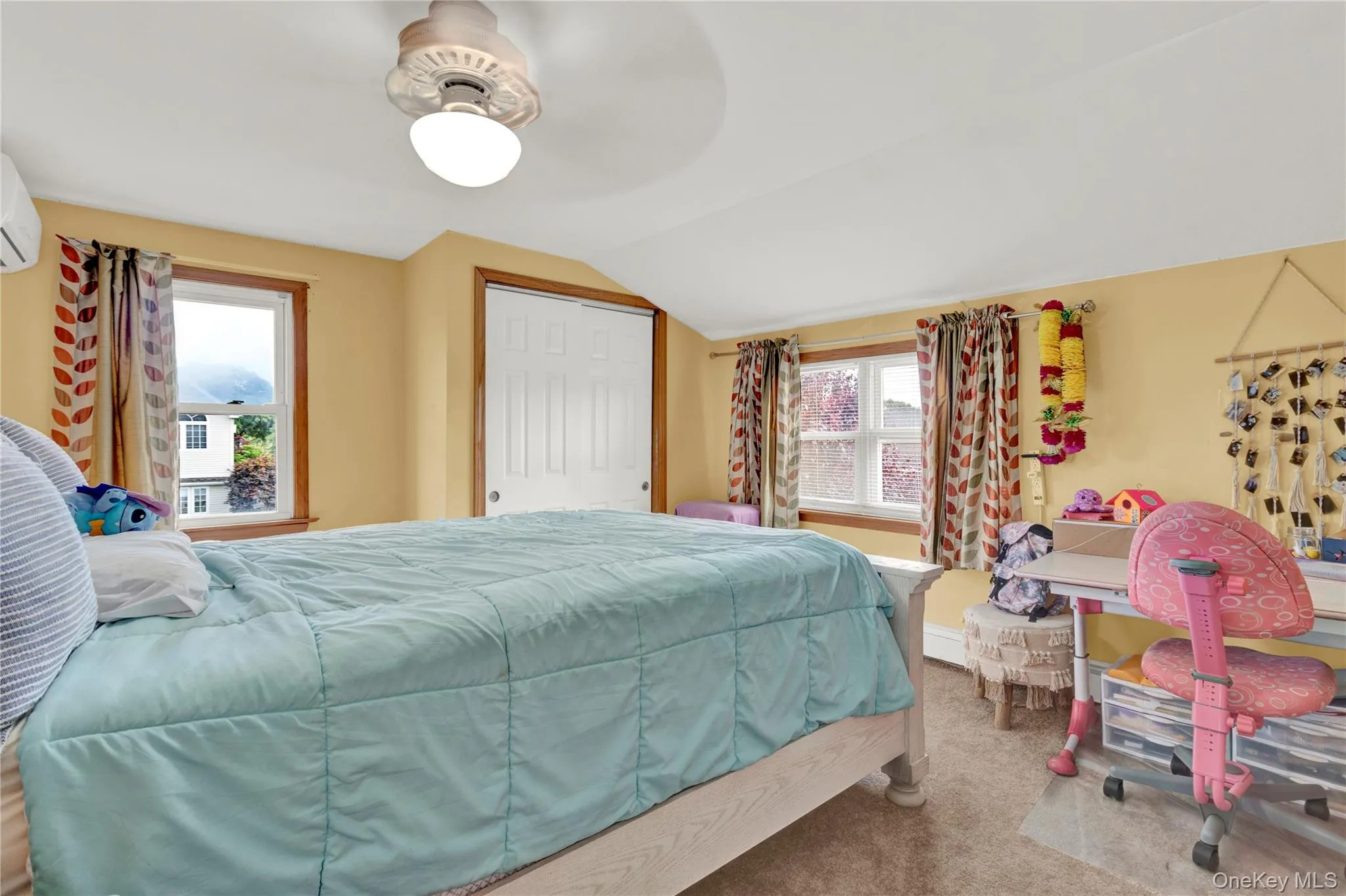 Carpeted bedroom featuring vaulted ceiling, a closet, a ceiling fan, and an AC wall unit Carpeted bedroom featuring vaulted ceiling, a closet, a ceiling fan, and an AC wall unit