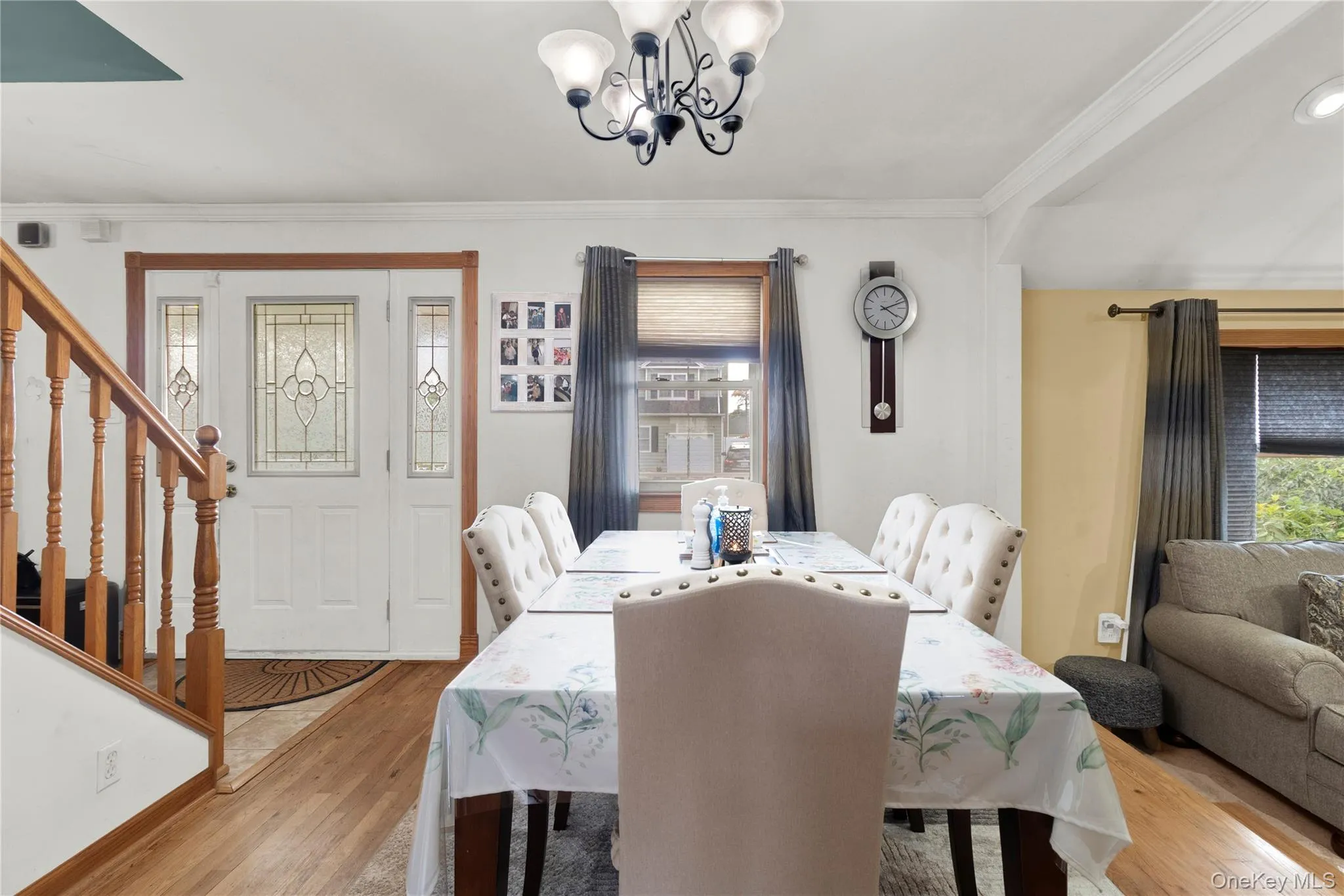 Dining space featuring ornamental molding, wood finished floors, a chandelier, and stairs Dining space featuring ornamental molding, wood finished floors, a chandelier, and stairs