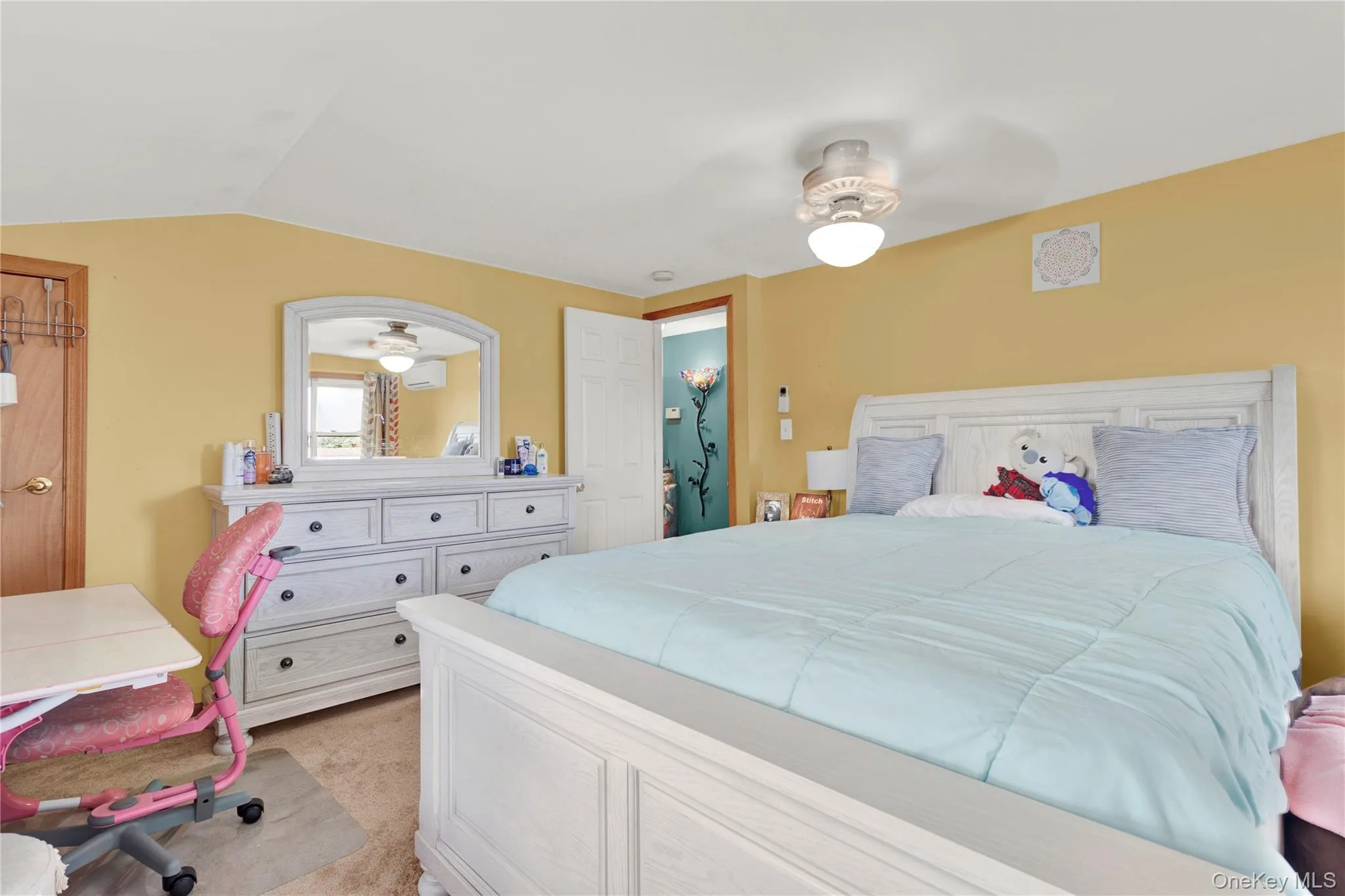 Bedroom with ceiling fan, lofted ceiling, an AC wall unit, and light colored carpet Bedroom with ceiling fan, lofted ceiling, an AC wall unit, and light colored carpet