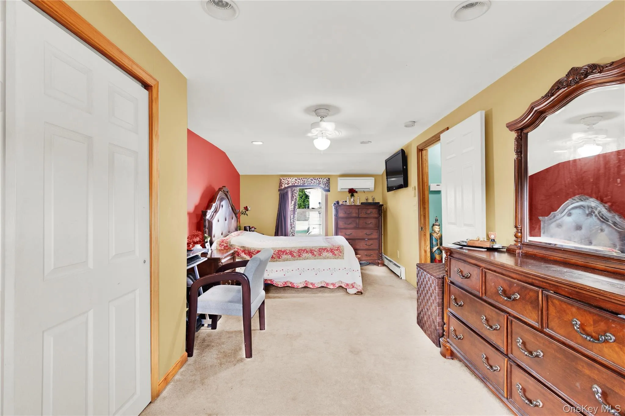 Bedroom featuring light colored carpet, ceiling fan, a baseboard heating unit, a wall mounted AC, and recessed lighting Bedroom featuring light colored carpet, ceiling fan, a baseboard heating unit, a wall mounted AC, and recessed lighting