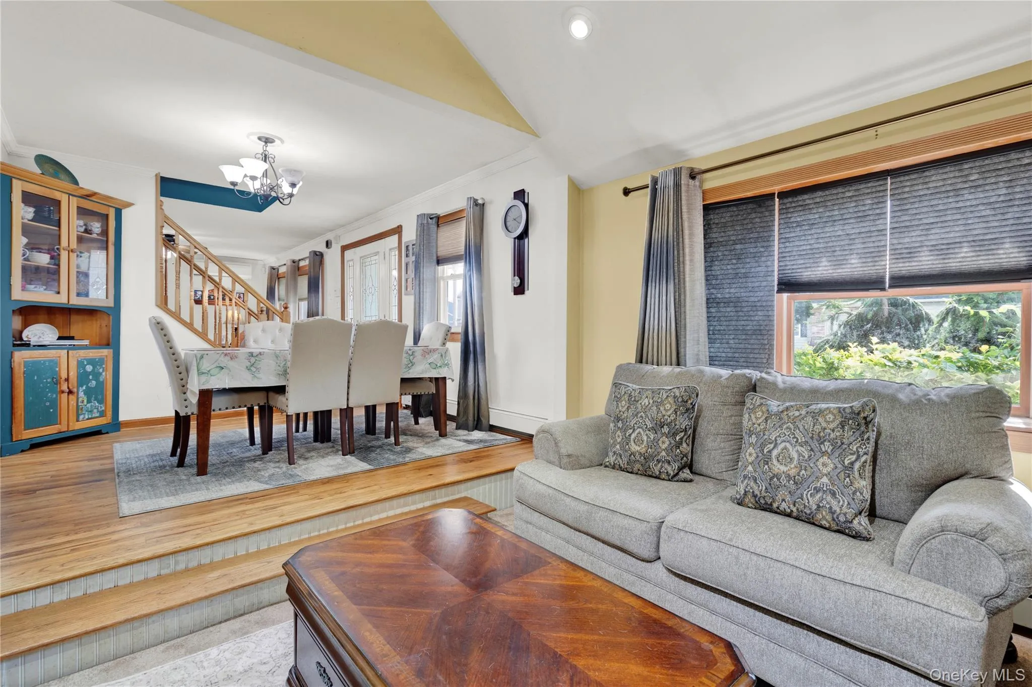 Living area with light wood-style flooring, a chandelier, and stairway Living area with light wood-style flooring, a chandelier, and stairway