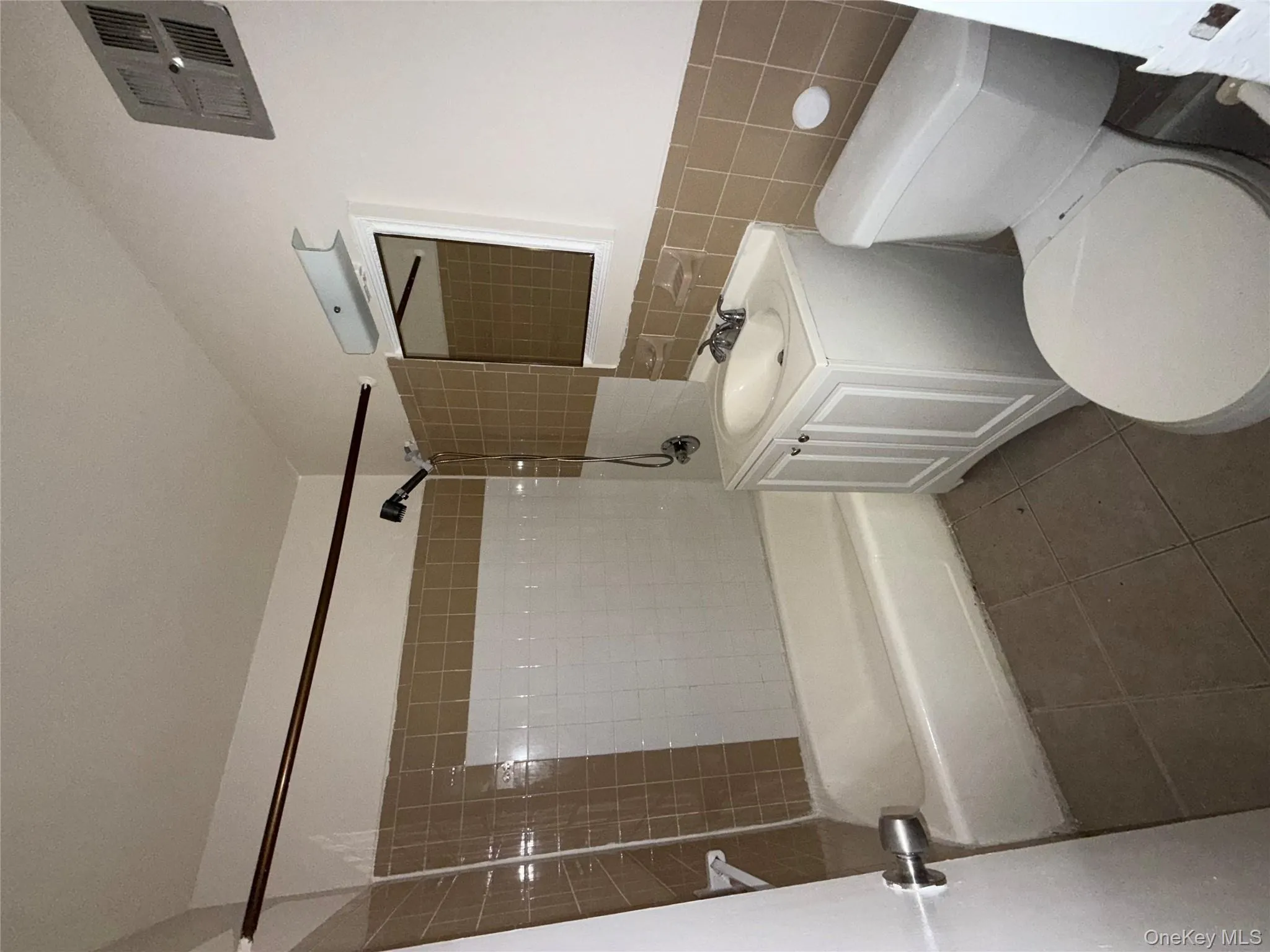 Bathroom with tile walls, vanity, shower / tub combination, dark tile patterned floors, and a wainscoted wall Bathroom with tile walls, vanity, shower / tub combination, dark tile patterned floors, and a wainscoted wall