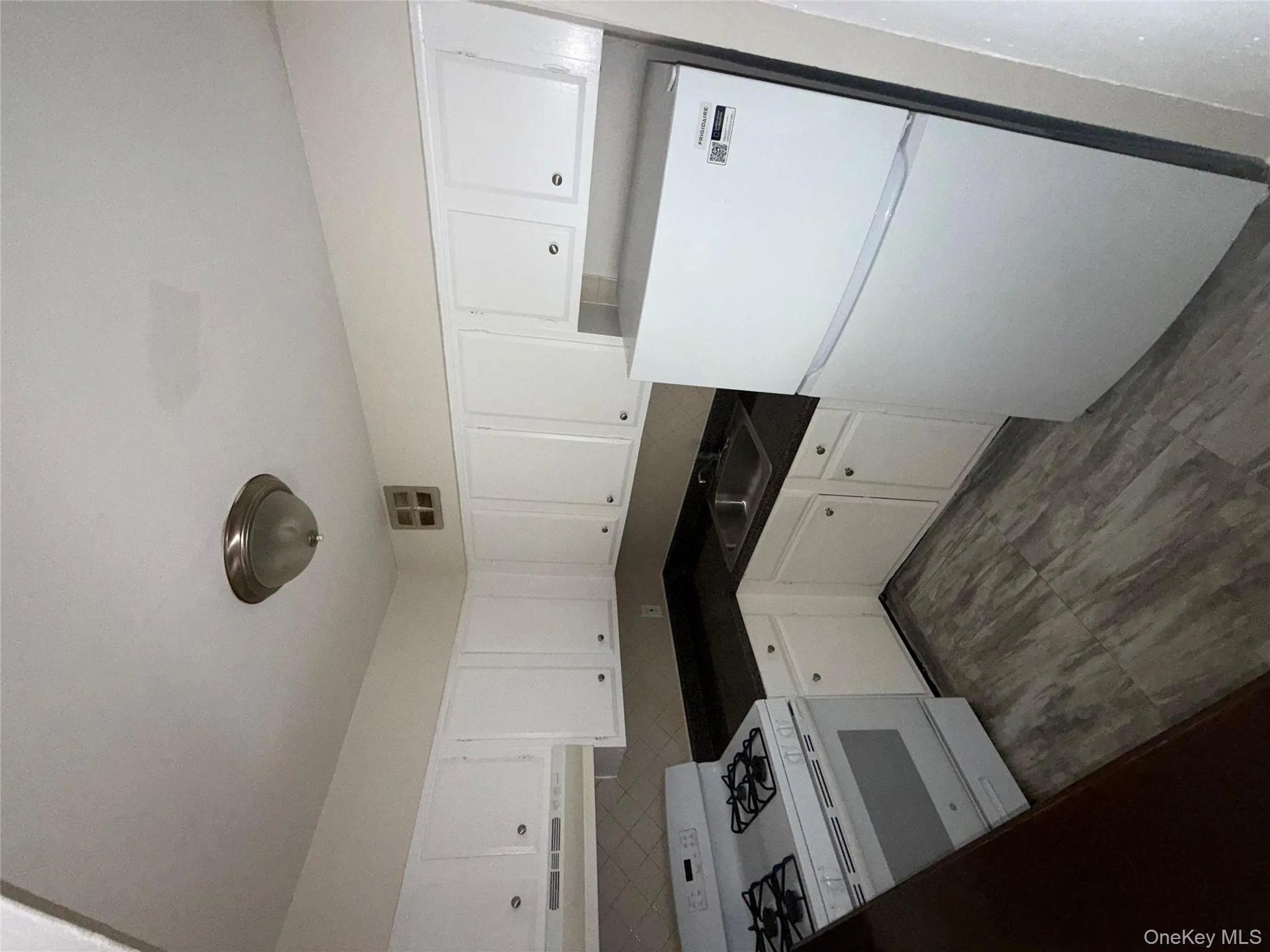 Kitchen featuring dark countertops, white refrigerator, stove, white cabinets, and range hood Kitchen featuring dark countertops, white refrigerator, stove, white cabinets, and range hood