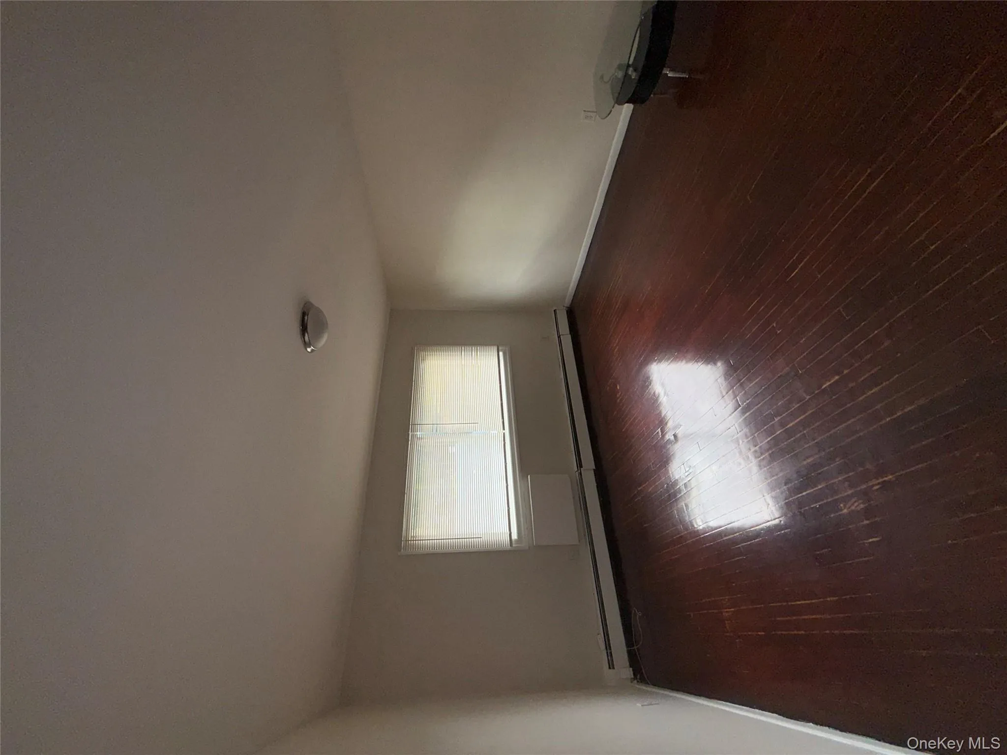 Unfurnished room with baseboard heating and dark wood-type flooring Unfurnished room with baseboard heating and dark wood-type flooring