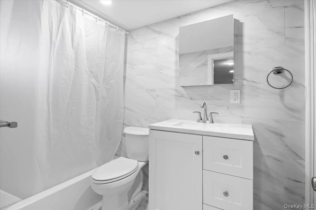 Bathroom with tile walls, vanity, and shower / bath combo Bathroom with tile walls, vanity, and shower / bath combo