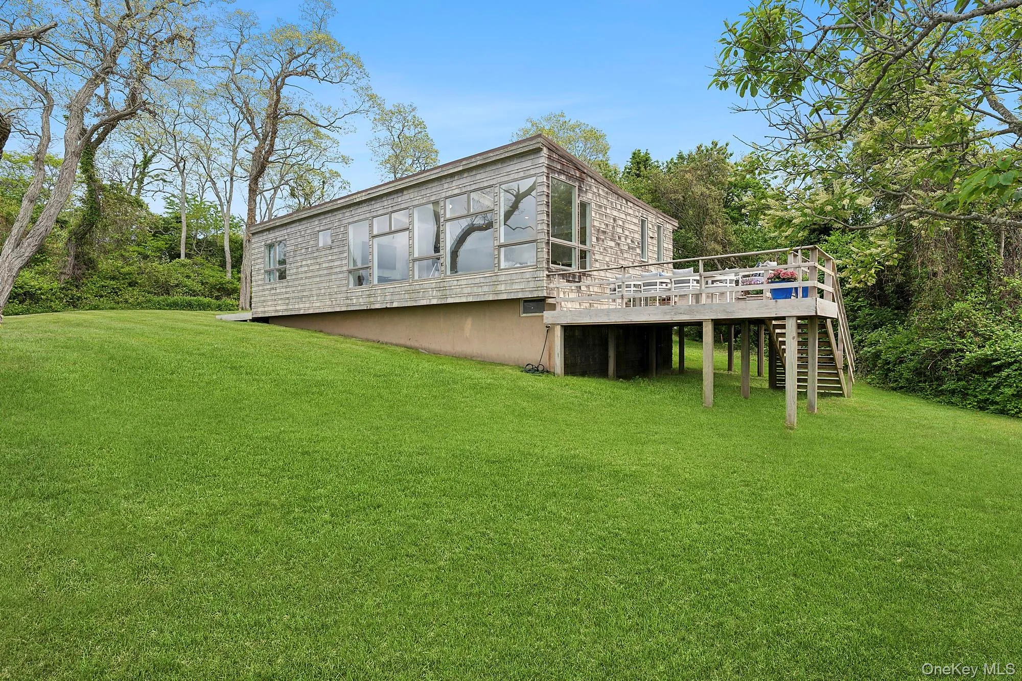 Back of property featuring stairway, a wooden deck, and a yard Back of property featuring stairway, a wooden deck, and a yard