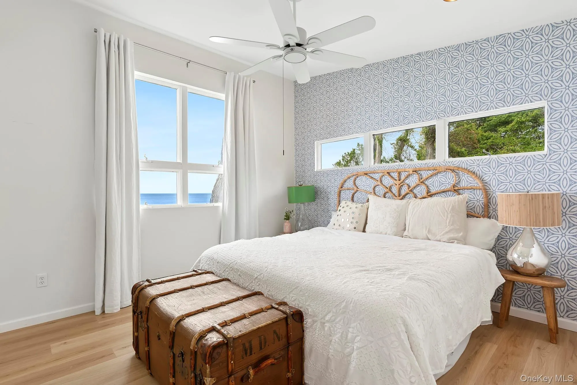 Bedroom featuring wallpapered walls, a water view, an accent wall, a ceiling fan, and light wood-type flooring Bedroom featuring wallpapered walls, a water view, an accent wall, a ceiling fan, and light wood-type flooring