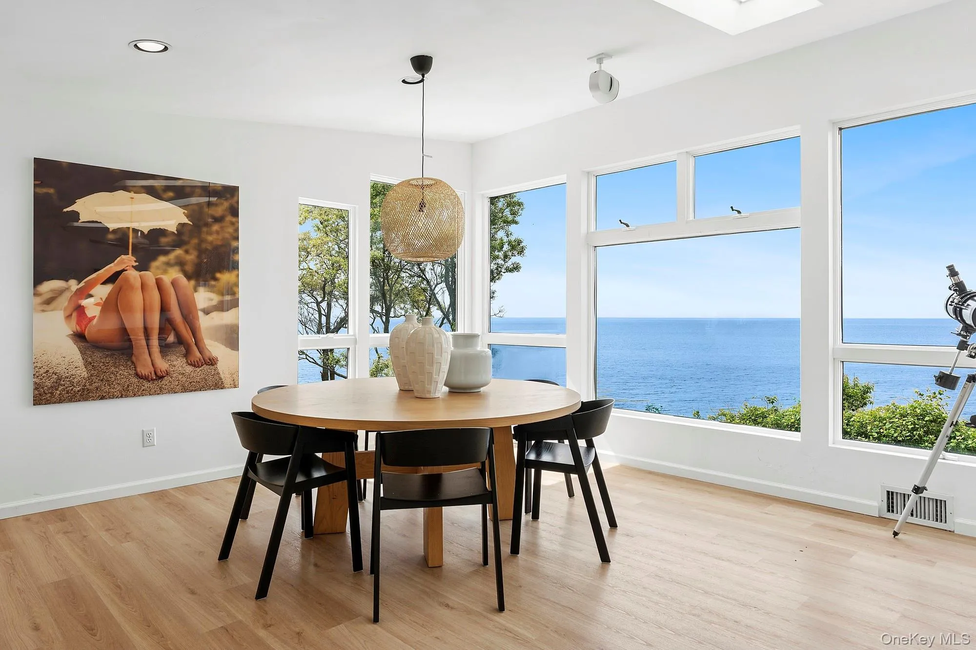 Dining space featuring light wood-style floors, a water view, a skylight, and recessed lighting Dining space featuring light wood-style floors, a water view, a skylight, and recessed lighting