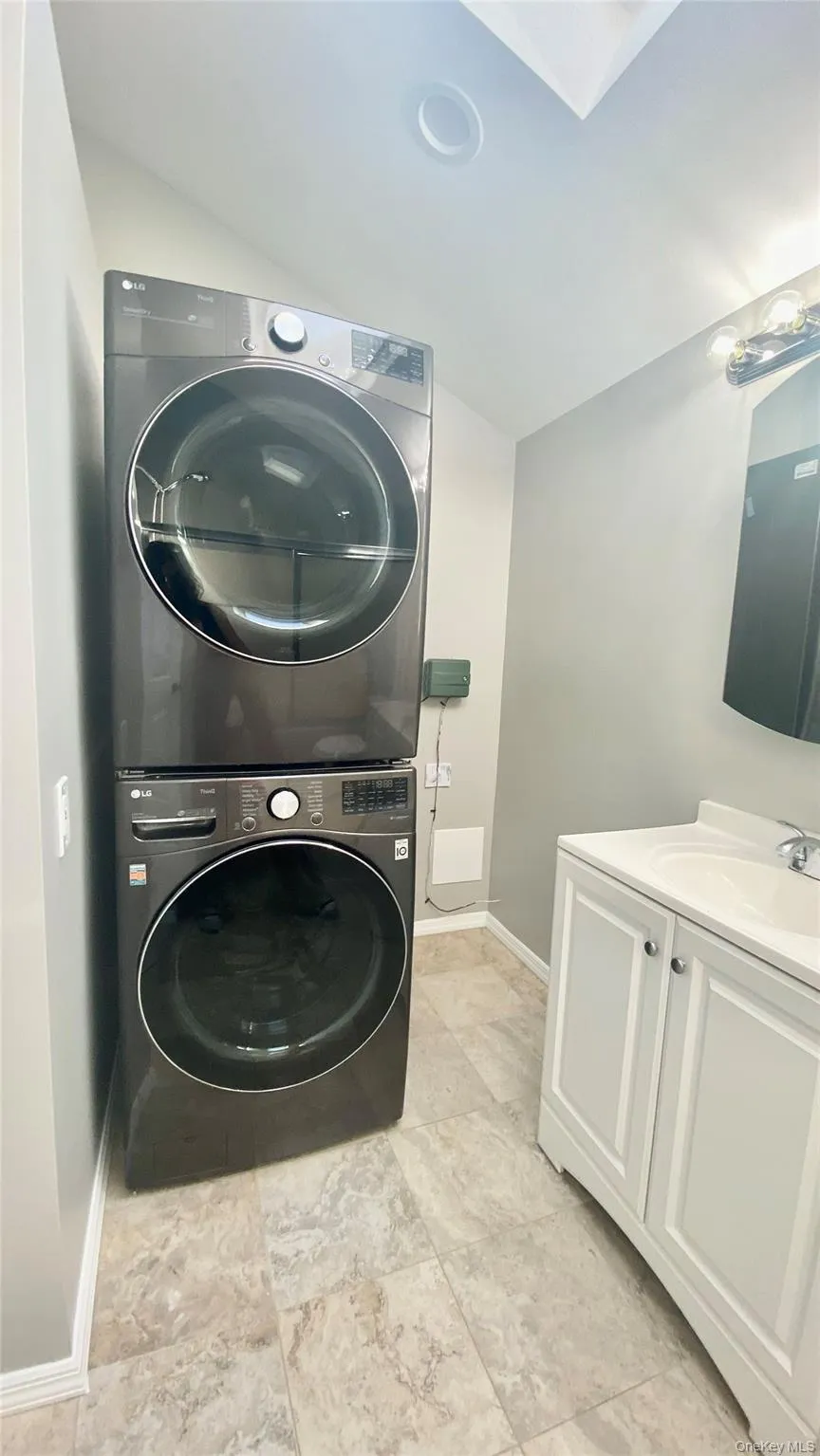 Washroom with stacked washer and clothes dryer and baseboards Washroom with stacked washer and clothes dryer and baseboards