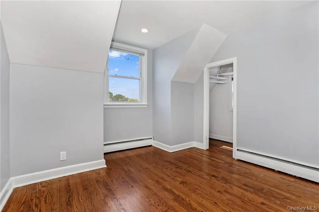 Bonus room with dark wood-type flooring, a baseboard radiator, and vaulted ceiling Bonus room with dark wood-type flooring, a baseboard radiator, and vaulted ceiling