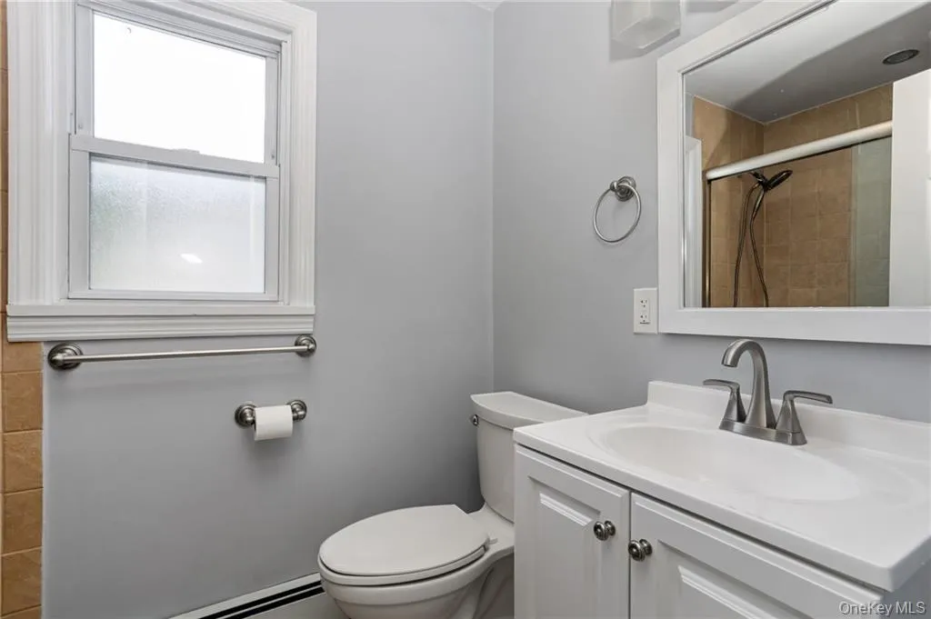 Bathroom featuring a shower stall, vanity, and a baseboard radiator Bathroom featuring a shower stall, vanity, and a baseboard radiator